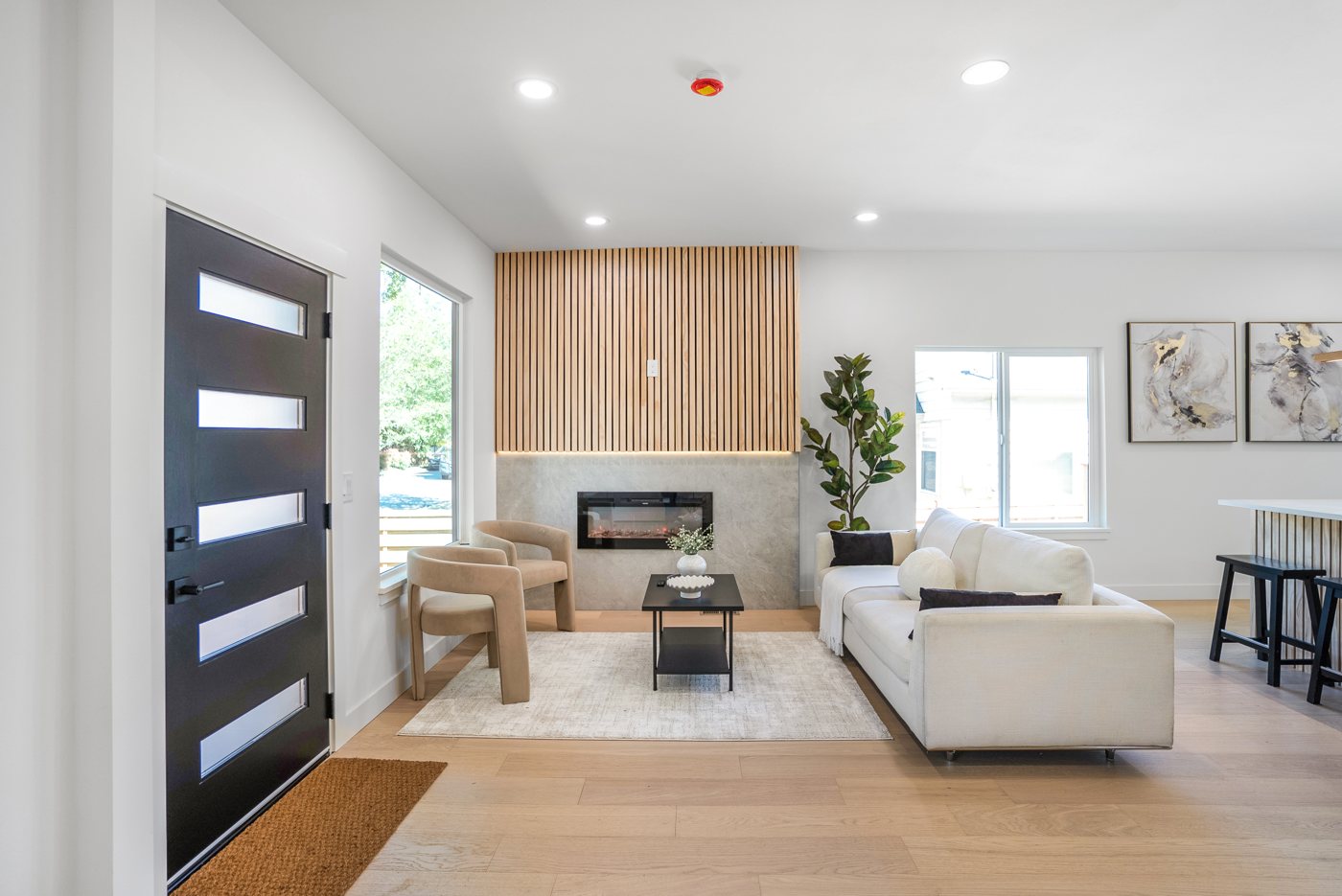Remodeled living room with a black entry door and a wood slat fireplace wall
